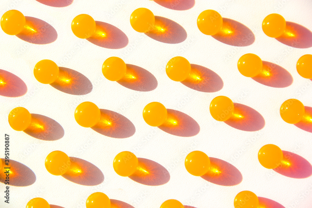 Small gold-orange balls with hard shadows. Pattern with gelatin capsule.