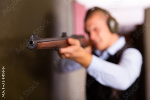 Closeup of muzzle of single barrelled shotgun on blurred background of aiming man