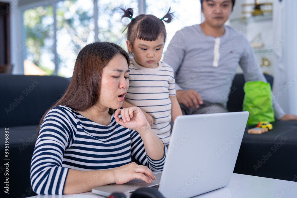 Young working mother work from home while babysitting her playful daughter at home. Working mother and daughter playing beside. Young working mother work from home while babysitting her playful daughter at home. Working mother and daughter playing beside.