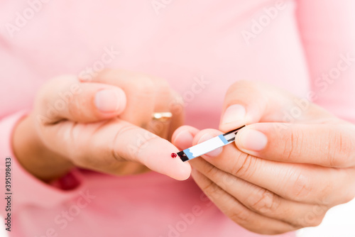 Closeup hands woman holding a plate measuring glucose test level checking with blood on a finger she monitors high blood sugar diabetes and glycemic health care concept isolated on white background