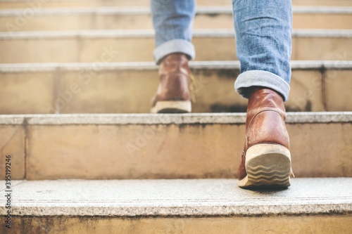 Close up image of young hipster wearing blue jeans and shoes leather walking at city stairs during travel destination to grow and learn experience.
