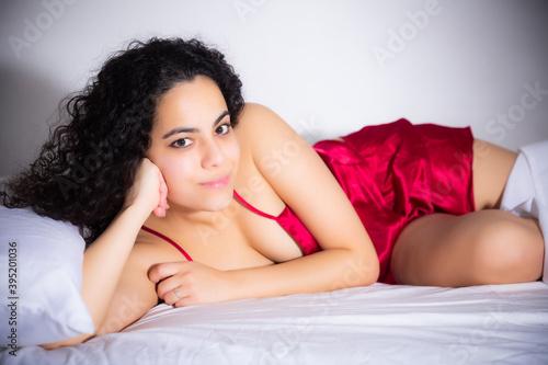 Attractive young woman with long hair erotically lying on bed