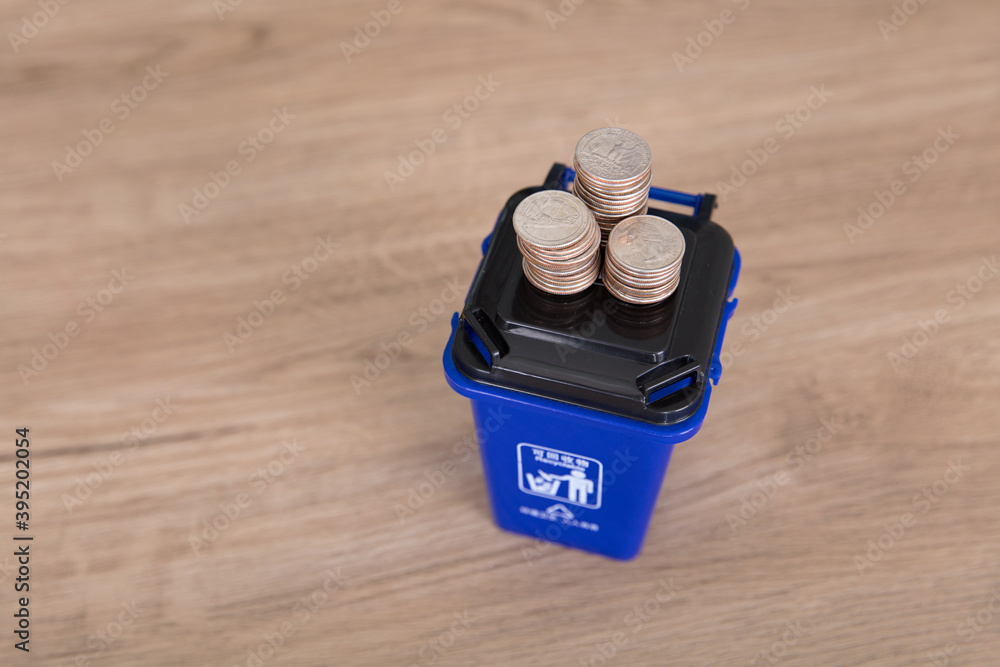 Fotografie Blue recyclable garbage bin model and dollar coins in sorted trash bin