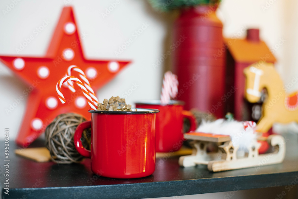 Red metal mug with tea and candy cane with Christmas decor Red metal mug with tea and candy cane with Christmas decor