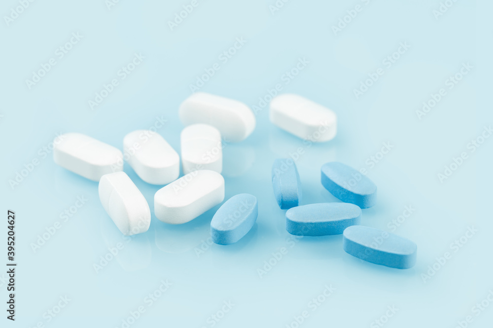 Medical background of many white and blue capsule tablets or pills on the table. Close up edgeless. Healthcare pharmacy and medicine concept. Painkillers or prescription drugs consumption