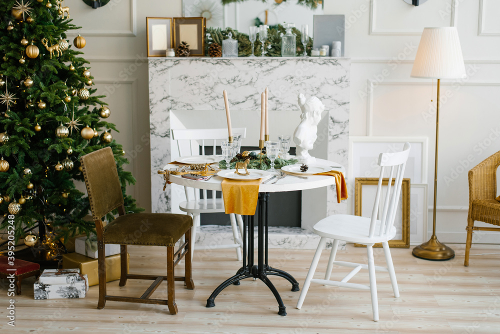 Classic interior of the vintage dining room with a marble fireplace, round table and various chairs near the Christmas tree