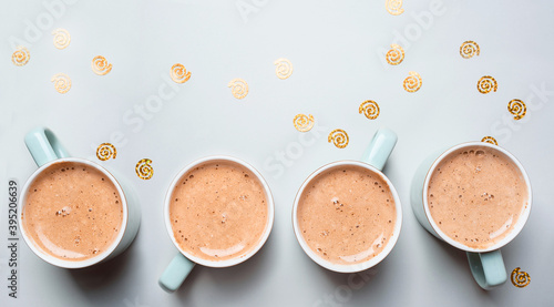 Four beautiful cups with milk with New Year's decor on a gray background.New Year's content