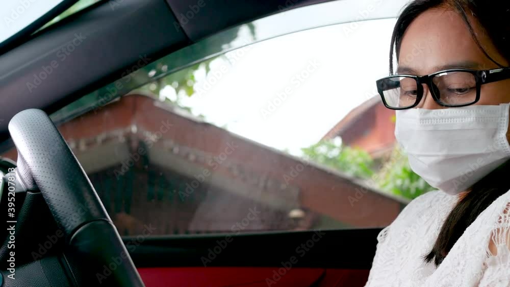 Young woman in a protective mask is spraying anti-bacterial or viral sanitizer spray on her hands in the car before driving. Concept of preventing the spread of the coronavirus. Young woman in a protective mask is spraying anti-bacterial or viral sanitizer spray on her hands in the car before driving. Concept of preventing the spread of the coronavirus.