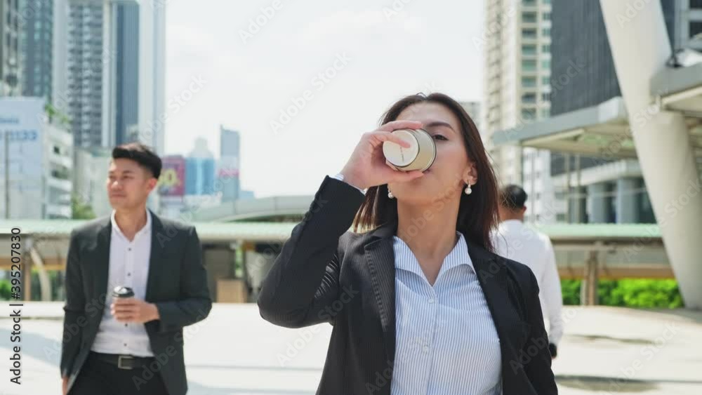 Asian young businesswoman drinking coffee while walking in the city. Asian young businesswoman drinking coffee while walking in the city.