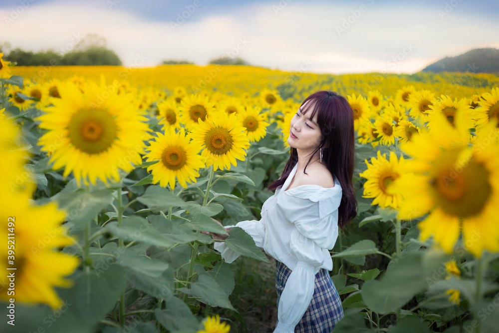 Happy enjoy summer girl in sunflower field in spring. Asian young woman joyful and smiling at sunset time Happy enjoy summer girl in sunflower field in spring. Asian young woman joyful and smiling at sunset time