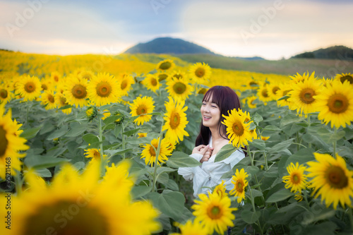 Happy enjoy summer girl in sunflower field in spring. Asian young woman joyful and smiling at sunset time