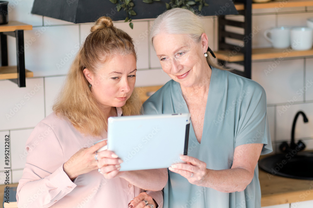 old mom and middle-aged daughter take selfies and talk via video link. Senior woman with her daughter looking at modern gadget indoors. relaxing together, different generations hobby pastime. old mom and middle-aged daughter take selfies and talk via video link. Senior woman with her daughter looking at modern gadget indoors. relaxing together, different generations hobby pastime.
