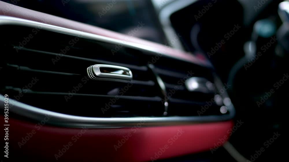 Close-up of a woman's hand adjusting the ventilation grill on the console inside the car. Close-up of a woman's hand adjusting the ventilation grill on the console inside the car.