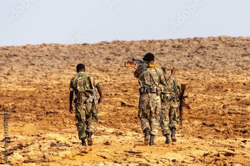 Back view of three Ethiopian soldiers walking in the wasteland