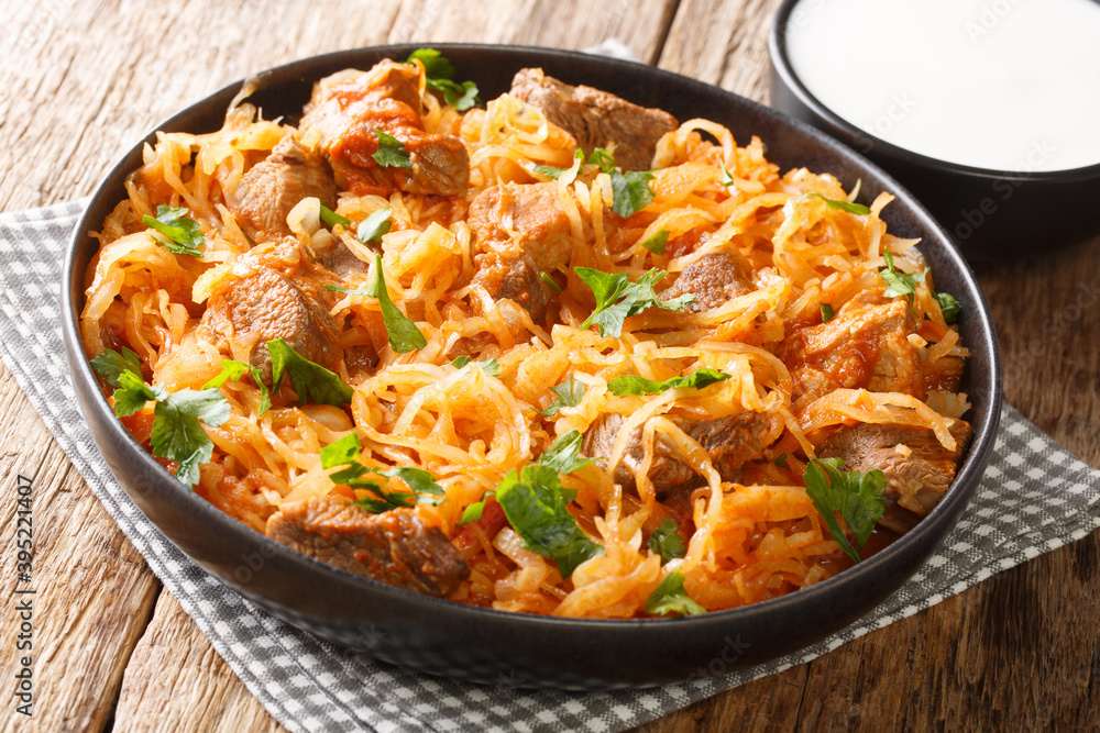 Delicious stewed sauerkraut with pork, onions and paprika close-up in a plate on the table. horizontal Delicious stewed sauerkraut with pork, onions and paprika close-up in a plate on the table. horizontal