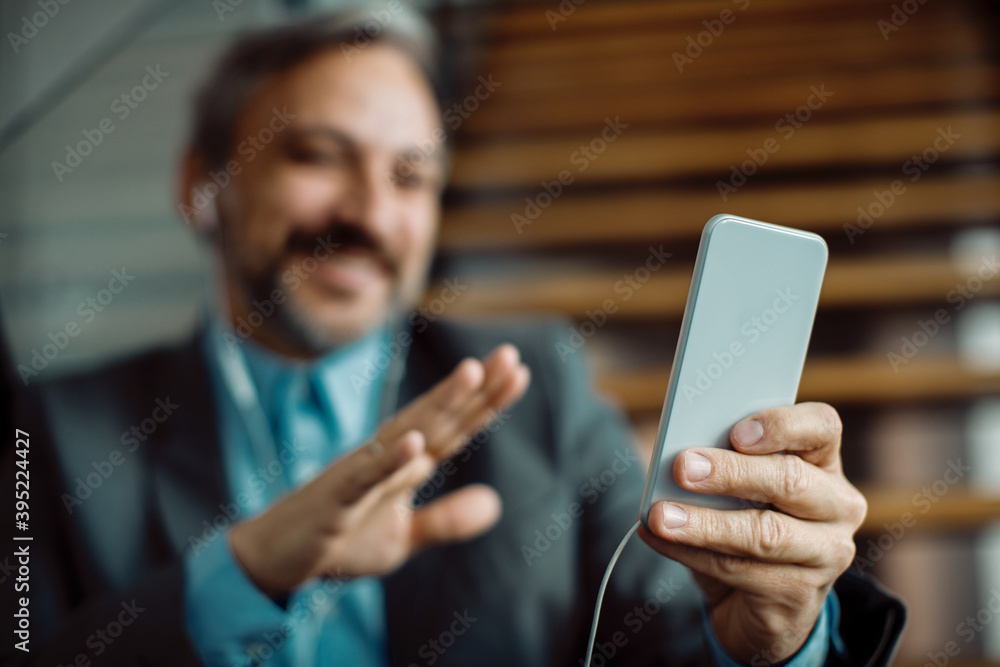 Close-up of businessman using mobile phone for a video call from the office. Close-up of businessman using mobile phone for a video call from the office.