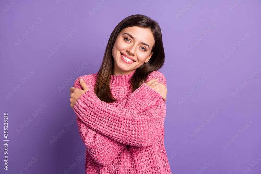 Photo portrait of nice smiling brunette girl wearing pink sweater hugging herself isolated on bright purple color background Photo portrait of nice smiling brunette girl wearing pink sweater hugging herself isolated on bright purple color background