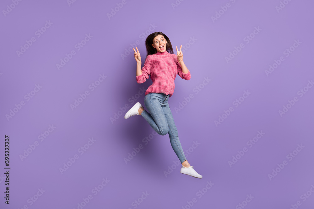 Full length body size photo of jumping high crazy woman showing v-sign gesture isolated on vivid violet color background Full length body size photo of jumping high crazy woman showing v-sign gesture isolated on vivid violet color background