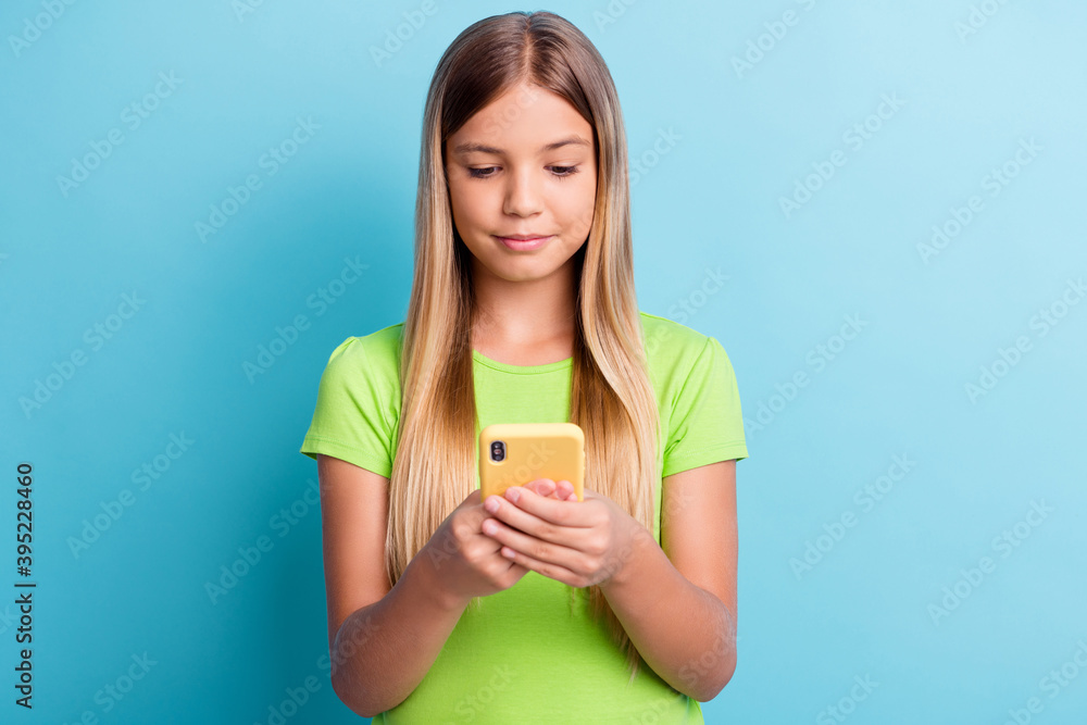 Photo of young serious charming lovely pretty girl using cellphone browsing internet isolated on blue color background Photo of young serious charming lovely pretty girl using cellphone browsing internet isolated on blue color background