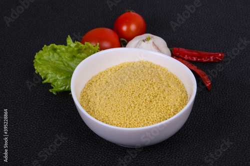 Raw couscous in the bowl served salad leaves, tomato and pepper photo