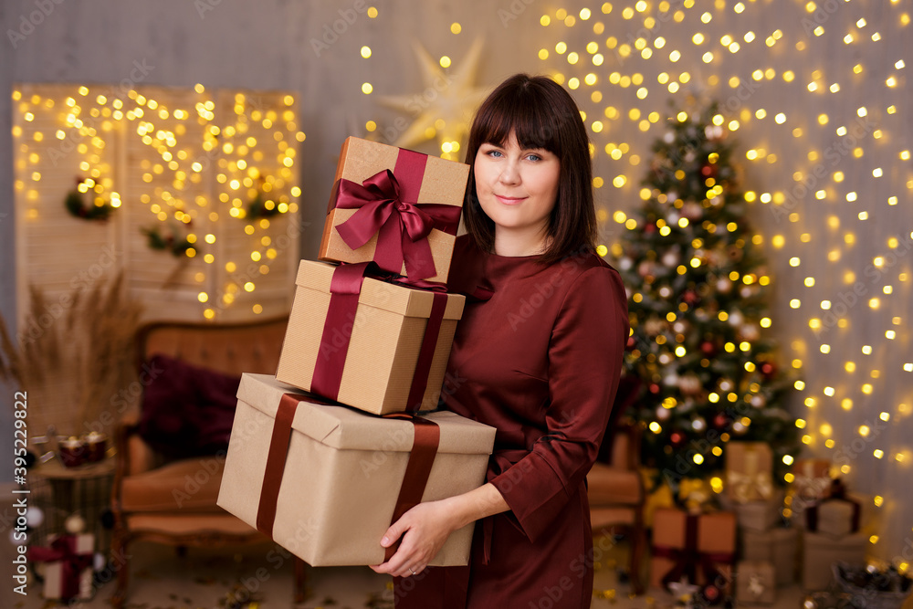 young beautiful woman holding heap of gift boxes over christmas background with Christmas tree and led lights young beautiful woman holding heap of gift boxes over christmas background with Christmas tree and led lights