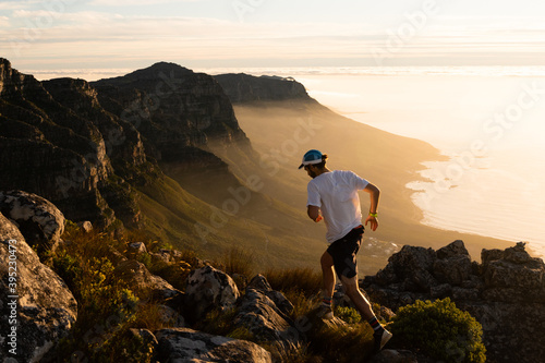 A person running along a mountain top at sunset 