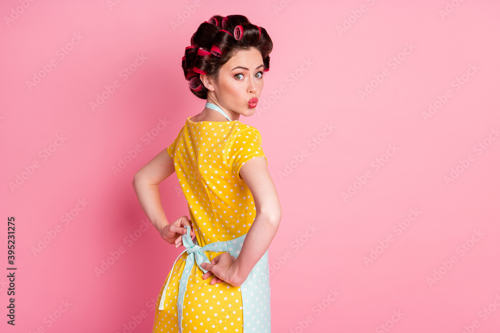 Back rear spine view photo of housewife with hair curlers wear apron send air kiss isolated pastel color background Back rear spine view photo of housewife with hair curlers wear apron send air kiss isolated pastel color background