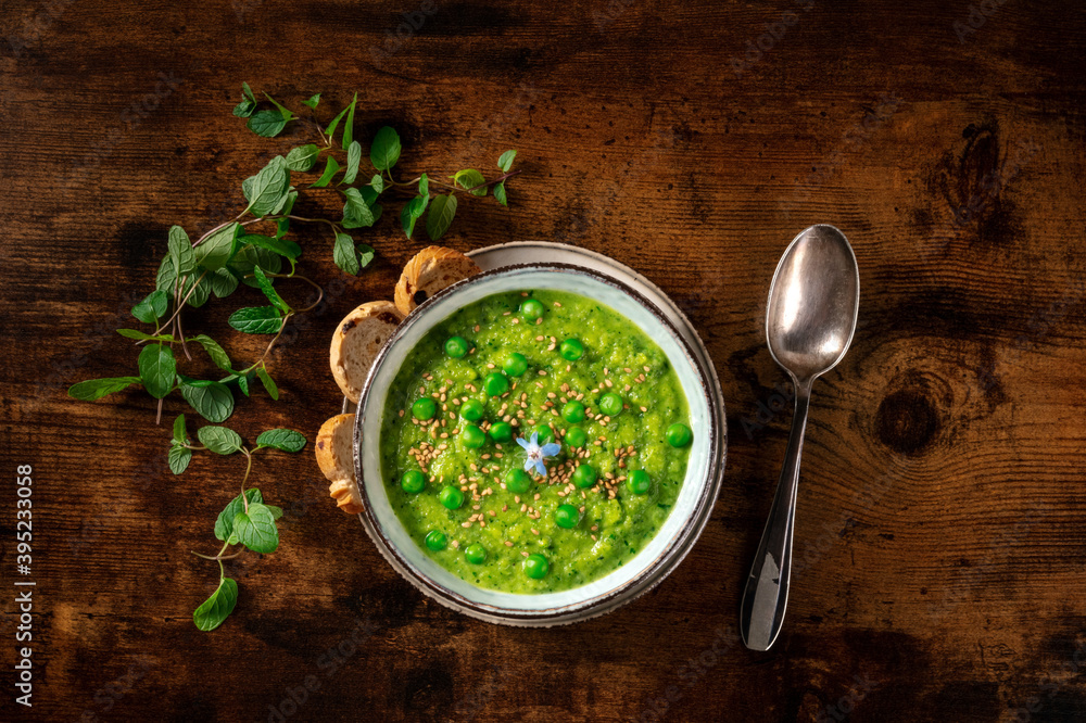 Vegan green soup, shot from the top with toasts and mint on a dark rustic wooden background Vegan green soup, shot from the top with toasts and mint on a dark rustic wooden background