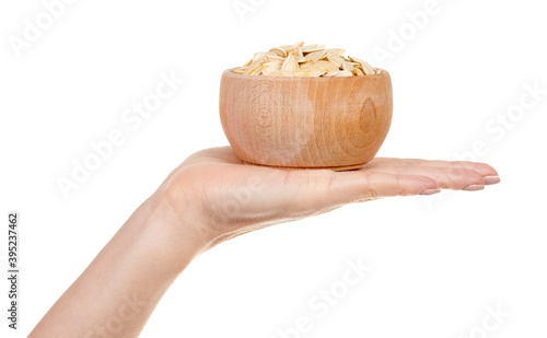 Hand with pumpkin seeds in wooden jar isolated on white background.