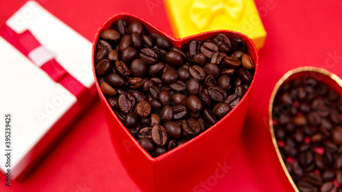 Colorful open box gift present with roasted coffee beans on red background. Concept Valentine's Day. Love symbol, copy empty space for text, heart shape. Brown shiny whole grains  © Volodymyr