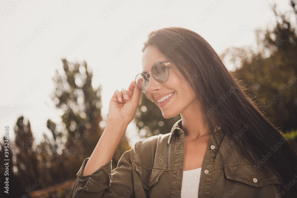 Photo of positive cheerful young lady palm adjust eyewear wear brown shirt spectacles park street outside