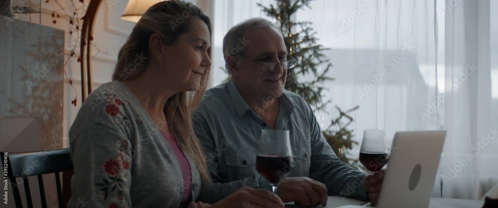 Senior mature adult Caucasian couple having a video call with friends or family on Christmas eve. Holidays celebration during COVID-19 Coronavirus lockdown Senior mature adult Caucasian couple having a video call with friends or family on Christmas eve. Holidays celebration during COVID-19 Coronavirus lockdown