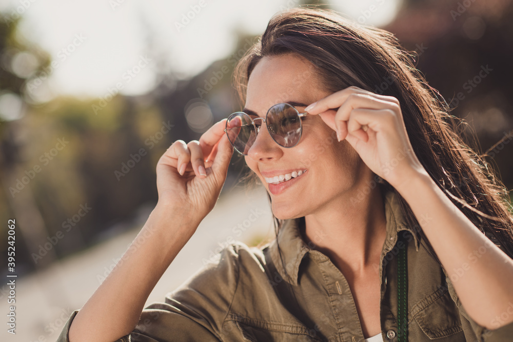 Profile side photo of charming shiny young woman dressed brown shirt smiling hands arms eyewear outdoors sunny city Profile side photo of charming shiny young woman dressed brown shirt smiling hands arms eyewear outdoors sunny city