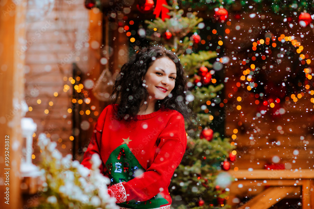 Woman posing on the open wooden terrace with Christmas decoration and snowing. Woman posing on the open wooden terrace with Christmas decoration and snowing.