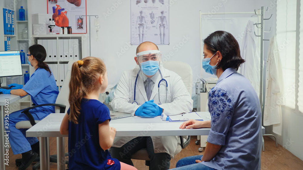 Radiologist with protection mask asking for child x-ray and checking it. Physician specialist in medicine providing health care services consultation treatment in hospital cabinet during covid-19