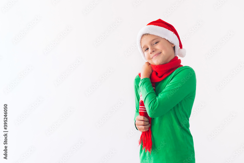 Portrait of happy boy wearing Santa Claus hat and wraps herself in scarf. Child having fun at Christmas time. Portrait of happy boy wearing Santa Claus hat and wraps herself in scarf. Child having fun at Christmas time.