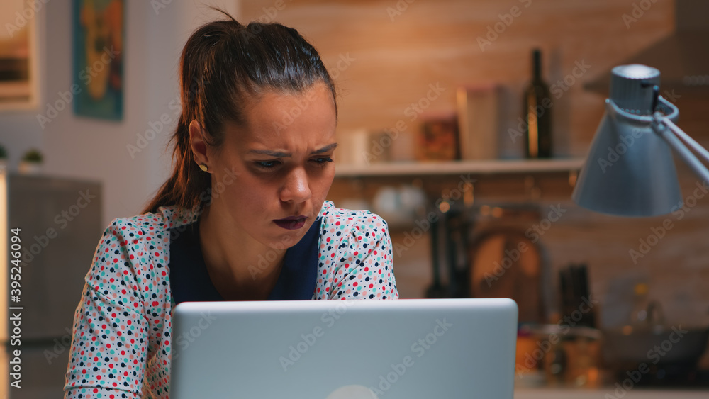 Tired freelancer squinting while reading emails working from kitchen home late at night in front of laptop. Busy focused employee using modern technology network wireless doing overtime writing Tired freelancer squinting while reading emails working from kitchen home late at night in front of laptop. Busy focused employee using modern technology network wireless doing overtime writing