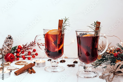 Two glasses of hot homemade mulled wine with oranges and rosemary in a New Year's atmosphere