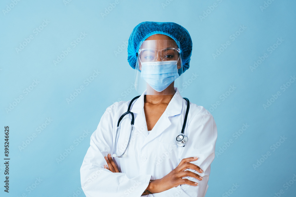 Portrait of a doctor in lab coat with face mask, face shield, and hair ppe with arms crossed Portrait of a doctor in lab coat with face mask, face shield, and hair ppe with arms crossed