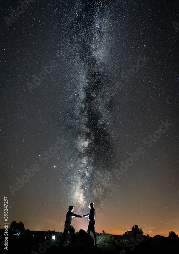 Two persons shaking hands against milky way