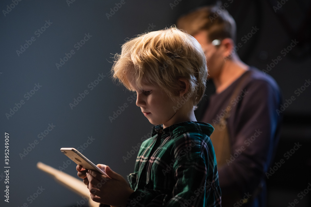 a small blond boy during a break in the labor lesson took a smartphone and communicates on social networks a small blond boy during a break in the labor lesson took a smartphone and communicates on social networks