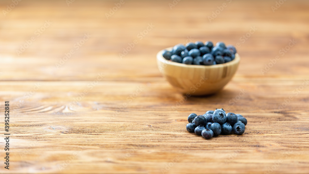 Brown bowl with blueberries on table with copy space. Wooden dish with little fresh healthy berries on desk with space for text. Heap of small raw fruit rich in vitamin on wooden desk. Brown bowl with blueberries on table with copy space. Wooden dish with little fresh healthy berries on desk with space for text. Heap of small raw fruit rich in vitamin on wooden desk.