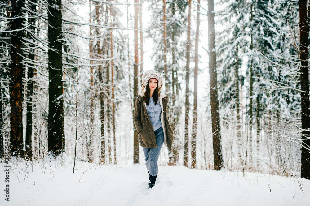 Funny young attractive girl with a turban from the scarf walking in the snow forest