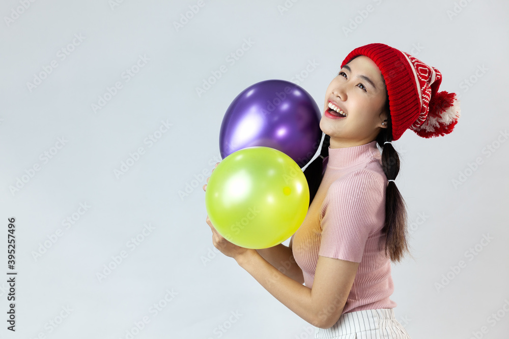 Portrait of cute asia woman wearing a red wool hat. Holding a balloon and smiling. On white background Portrait of cute asia woman wearing a red wool hat. Holding a balloon and smiling. On white background