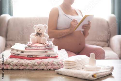 Pregnant woman is getting ready for the maternity hospital, packing baby stuff. pregnant woman preparing and planning baby clothes.  List of things in the hospital.  