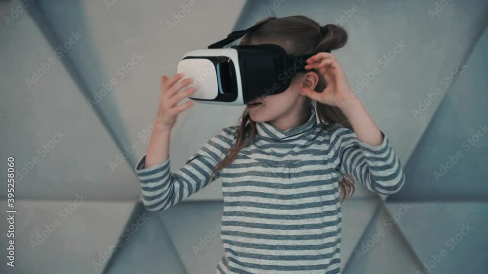 Little girl with virtual reality goggles. Child using a VR headset enjoying a video or interactive game. Little girl with virtual reality goggles. Child using a VR headset enjoying a video or interactive game.