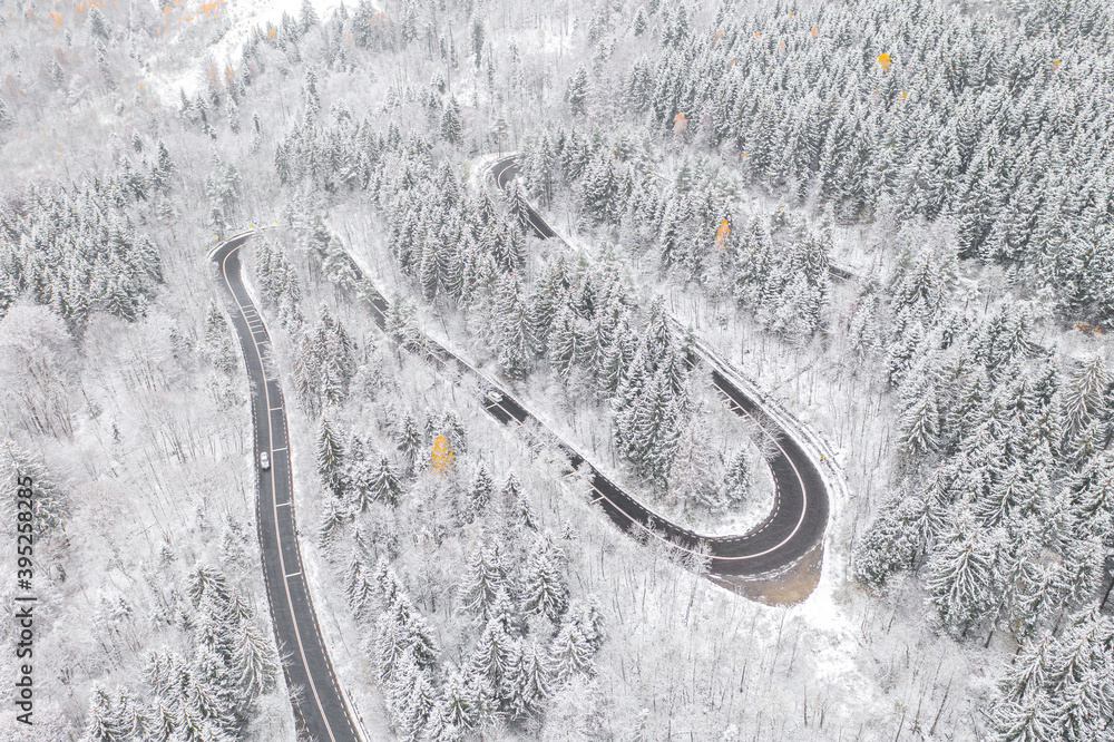 Aerial view of an amazing winding curved road through the mountains in winter snow landscape, motorway in Romania