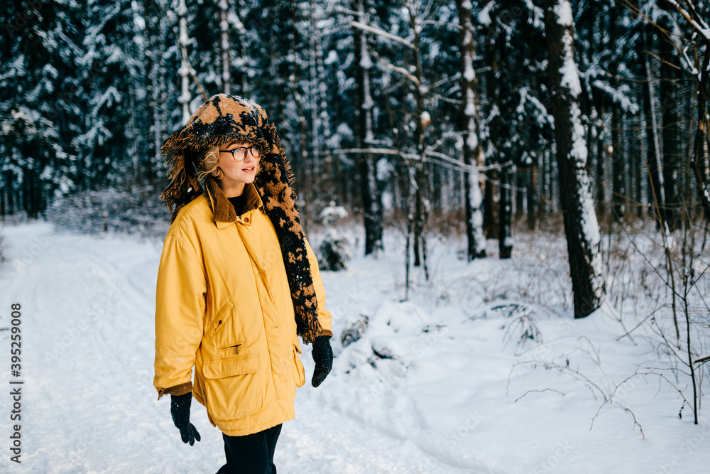 Funny strange young hipster girl with glasses and the scarf covering the head walking in the snow forest Funny strange young hipster girl with glasses and the scarf covering the head walking in the snow forest