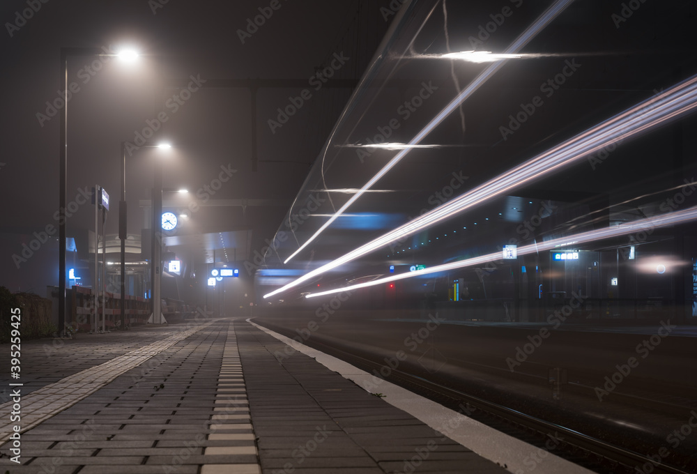 Train speeding at a railway platform at night.