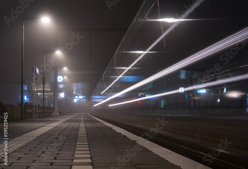 Train speeding at a railway platform at night.